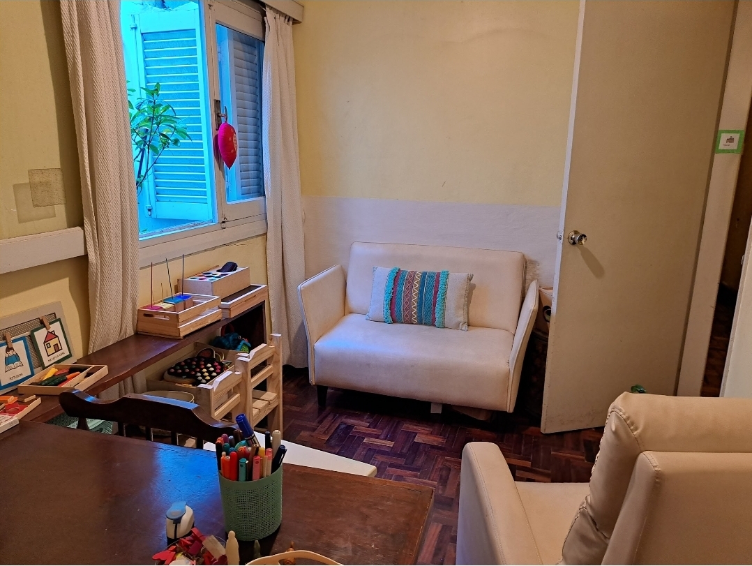 Consultorio cálido con sillón blanco, plantas y materiales terapéuticos en ambiente luminoso y acogedor